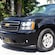 A large Chevy Tahoe SUV with trees in the background